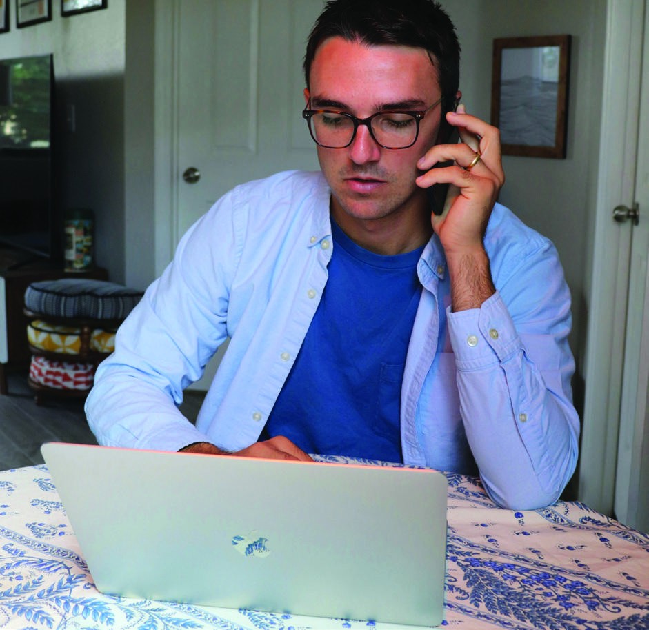 A person speaking on the phone beside a laptop